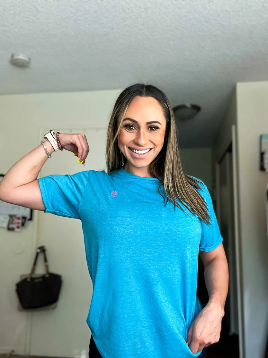 A customer flexing in an aqua RecyclenBrand tee with a pink trash-can logo